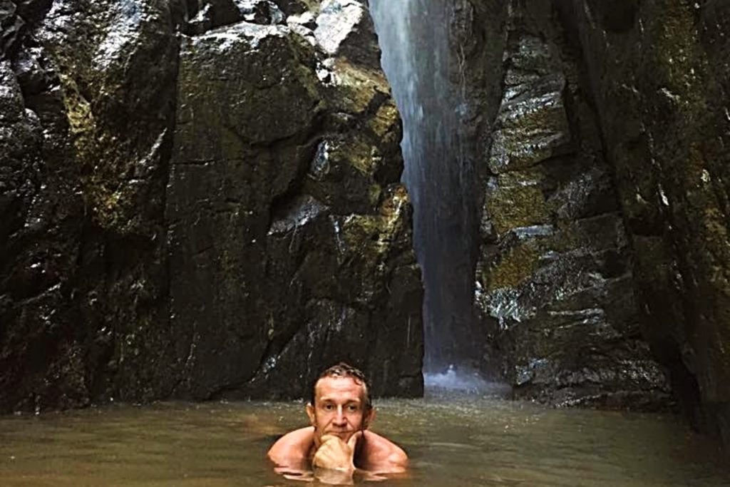 Muž koupající se ve vodopádech na Bali